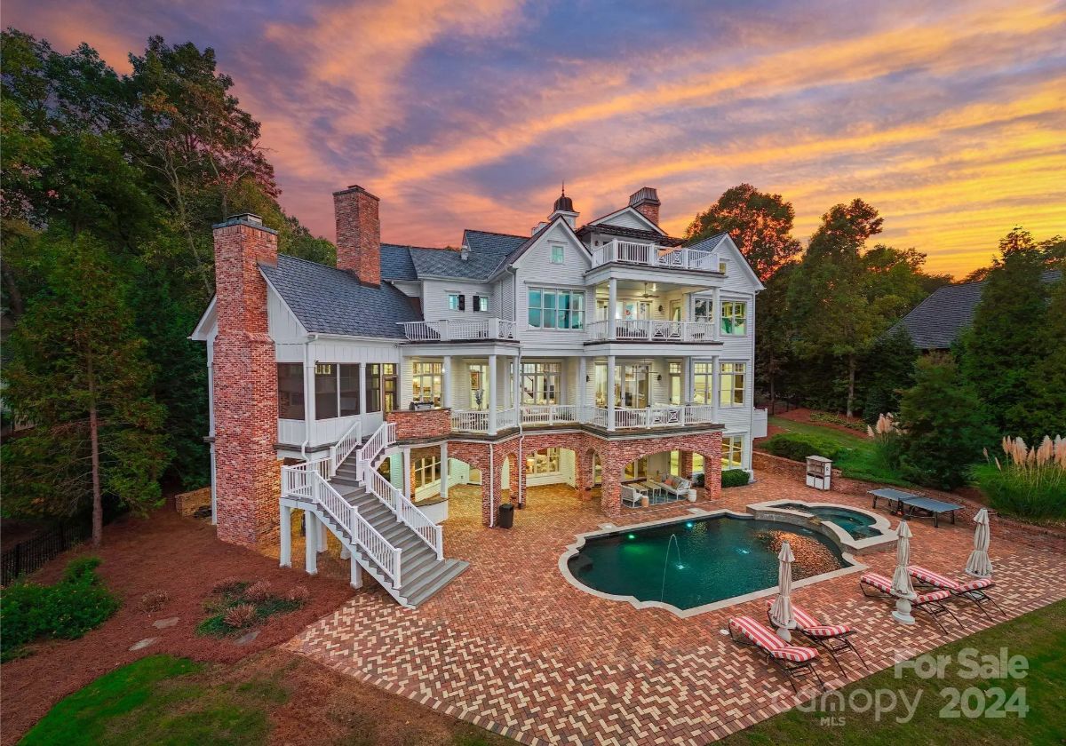 Rear view of the house at sunset showcasing multiple balconies and a beautiful pool area. 
