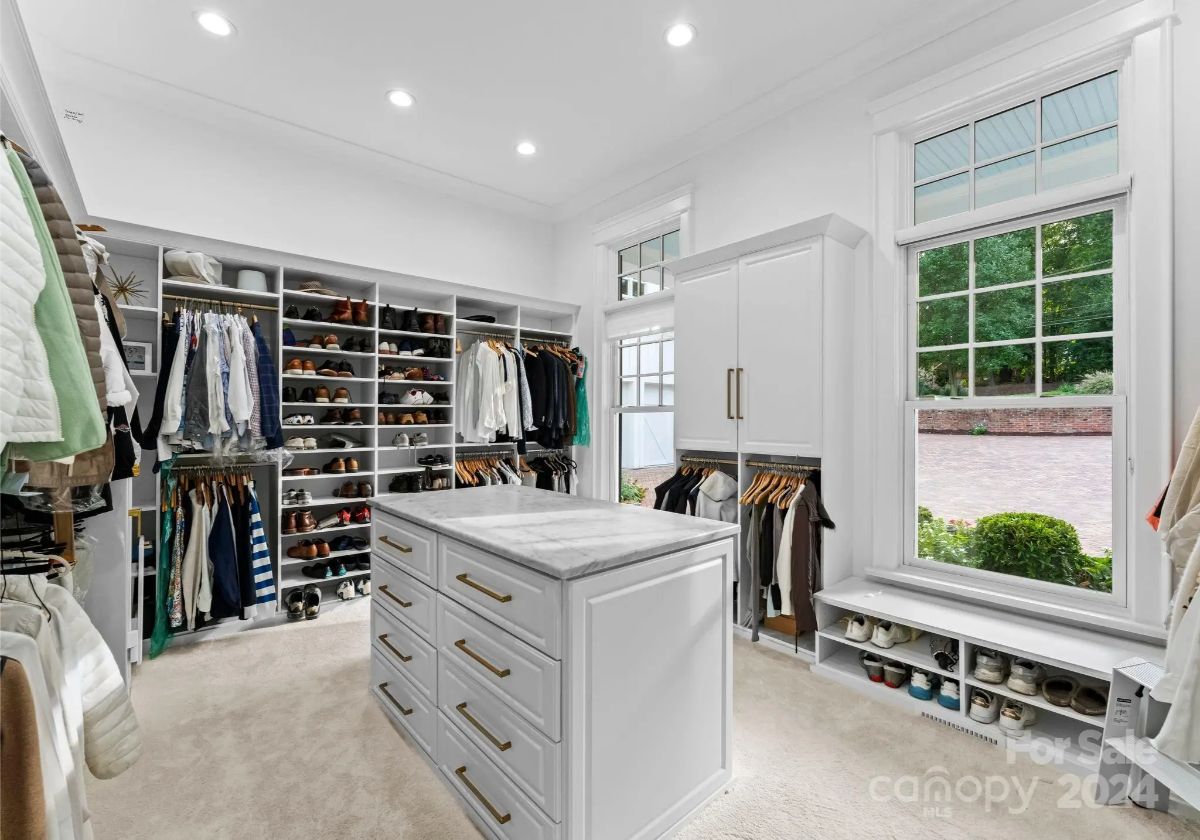 Custom walk-in closet with a center island, built-in shelves, and natural light from a large window. 