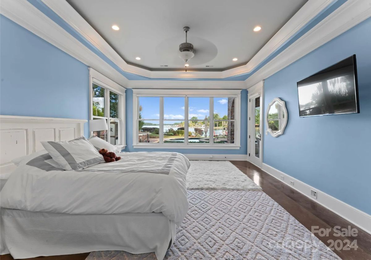 Second bedroom with tray ceiling, blue walls, and large windows capturing the waterfront. 