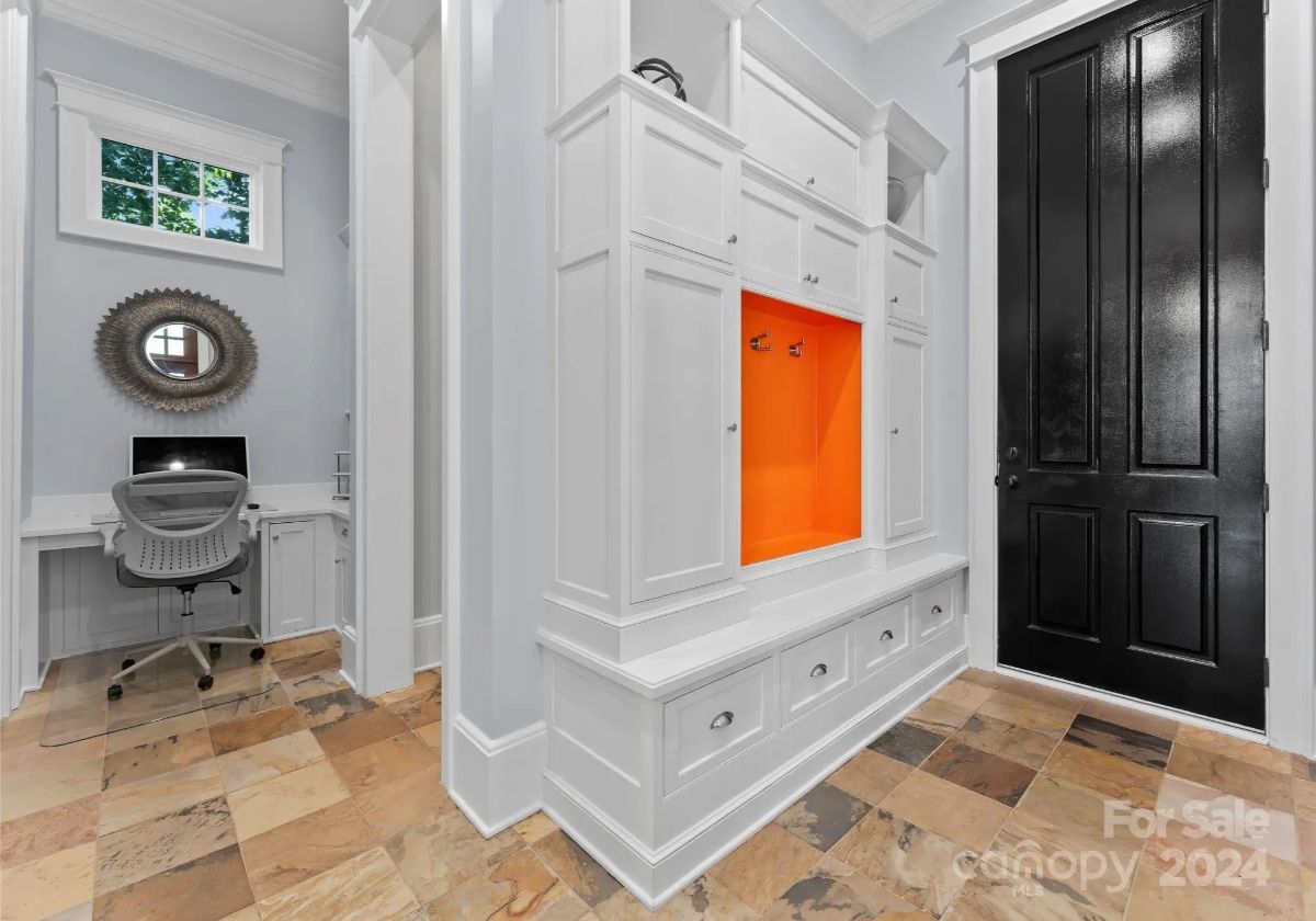 Built-in mudroom area with bright orange accent nook and an adjacent small desk workspace. 