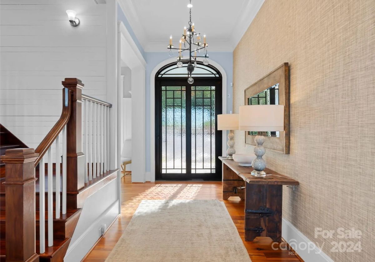 Bright and welcoming entryway featuring a black arched door and rustic console table. 