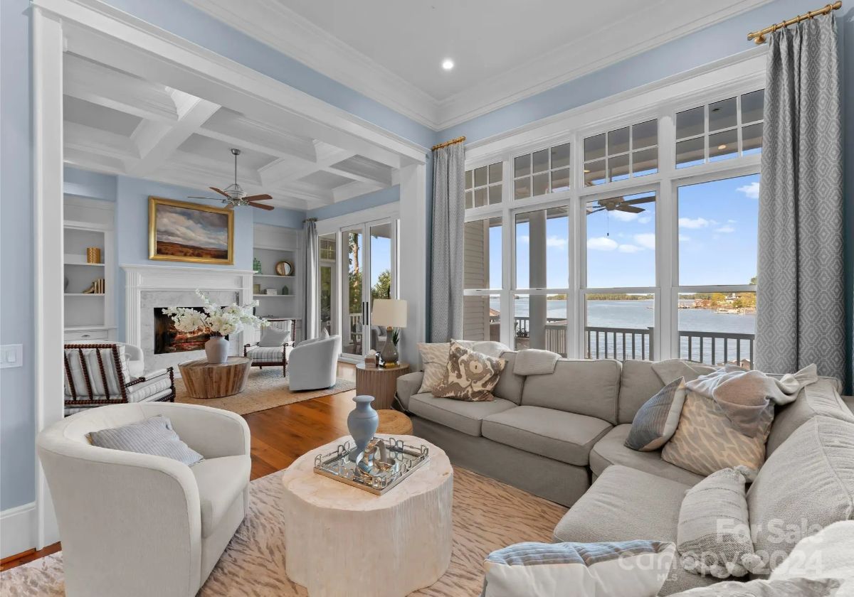 Living room with coffered ceilings, cozy seating, and large windows overlooking the lake. 