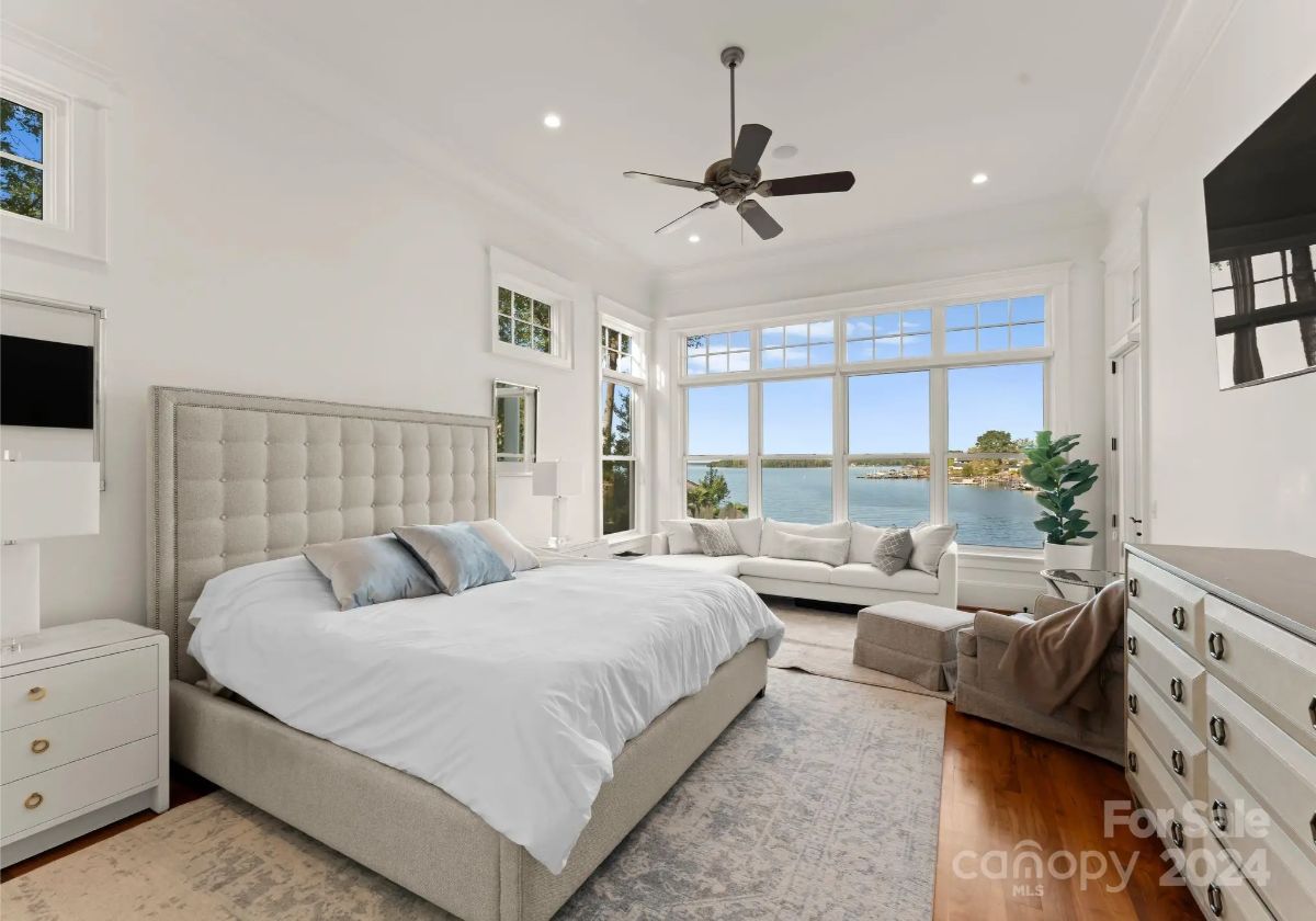 Spacious bedroom with large windows offering stunning lake views. 