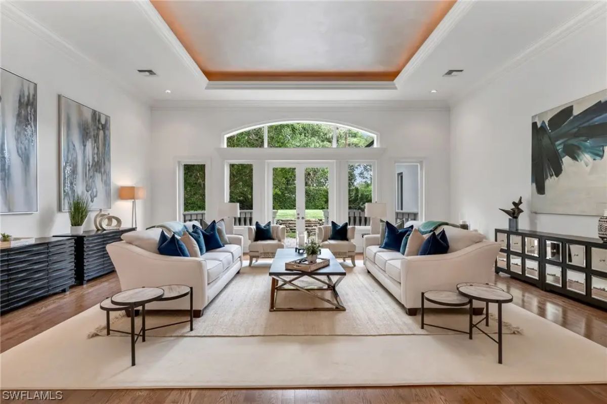Matching white sofas and chairs are arranged on a large cream rug.