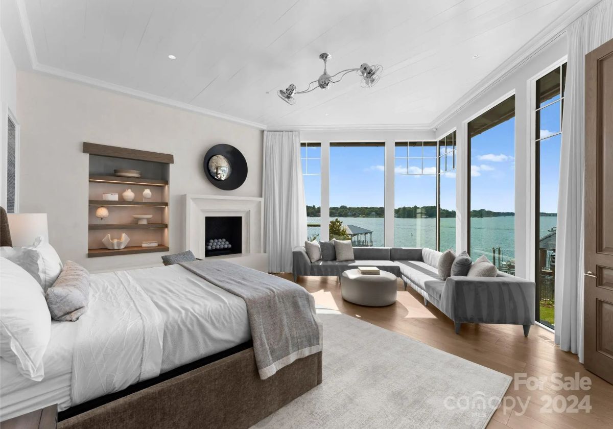 A dreamy bedroom suite unfolds toward the lake, with a cozy fireplace and elegant seating area. 