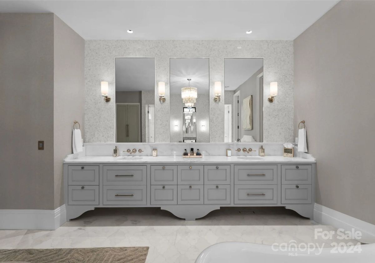 A long vanity stretches across a serene bathroom, where neutral tones and classic fixtures create timeless luxury. 