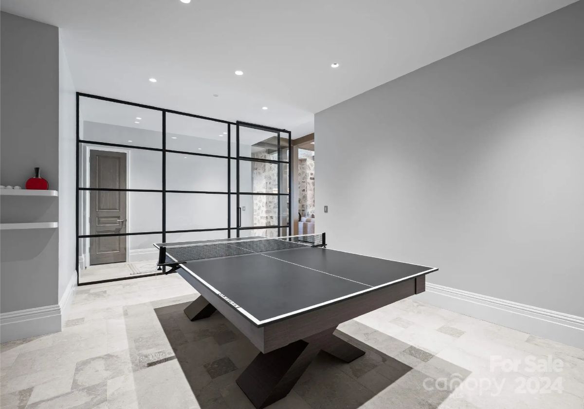 Glass walls enclose a minimalist ping-pong room, where modern design meets playful energy. 