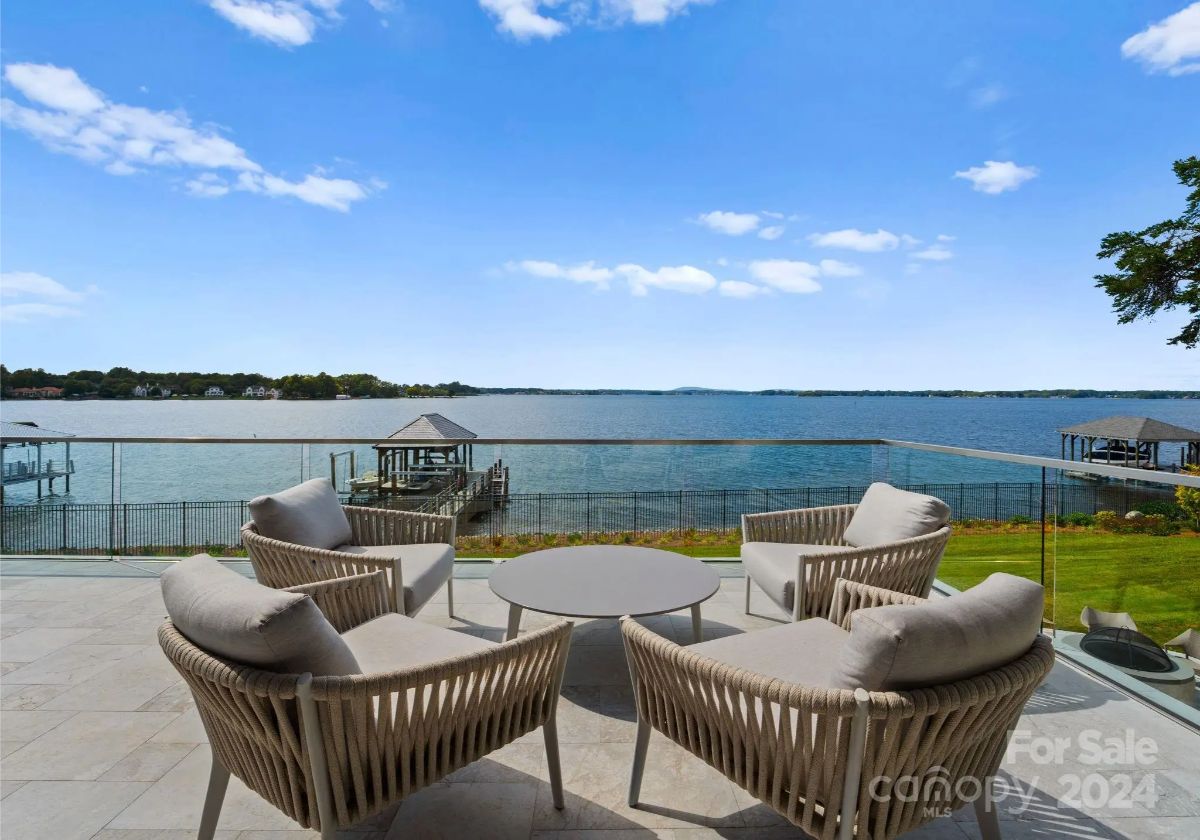 Woven chairs surround a sleek fire pit, offering front-row seats to endless waterfront tranquility. 
