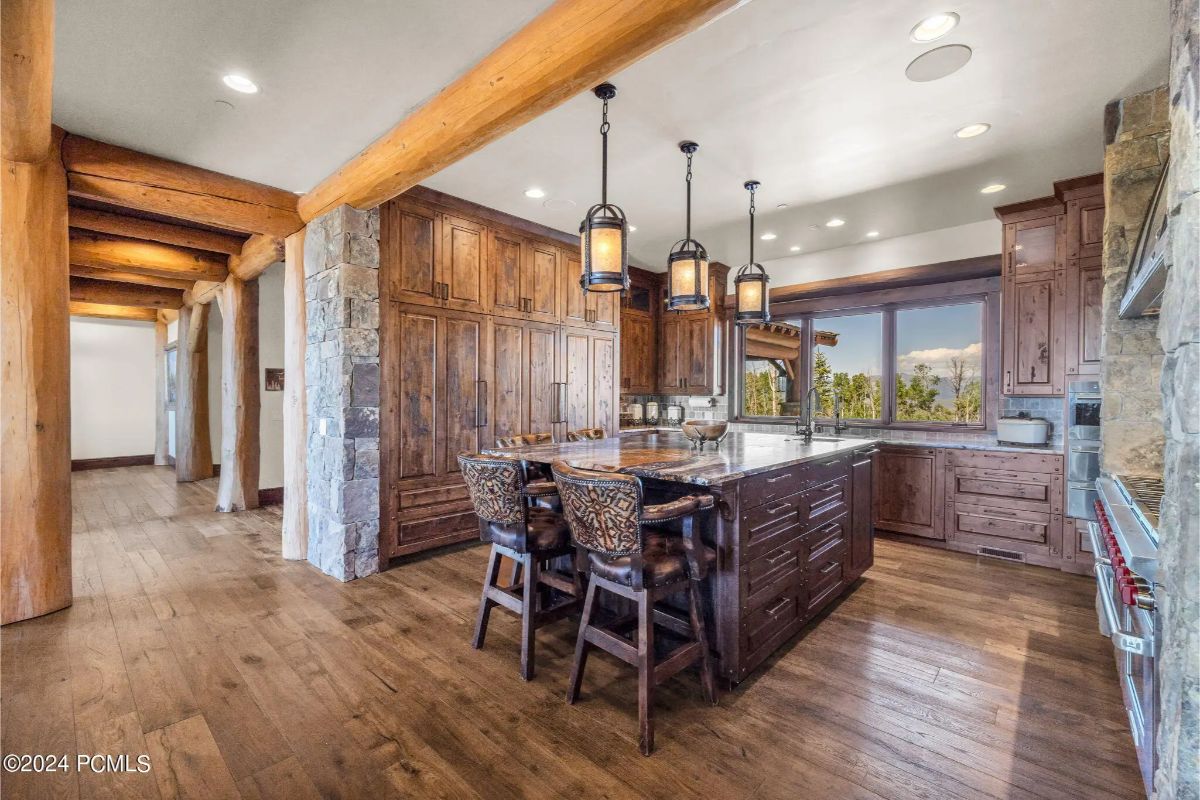 Wood cabinetry extends to the ceiling and surrounds a central island with bar seating.