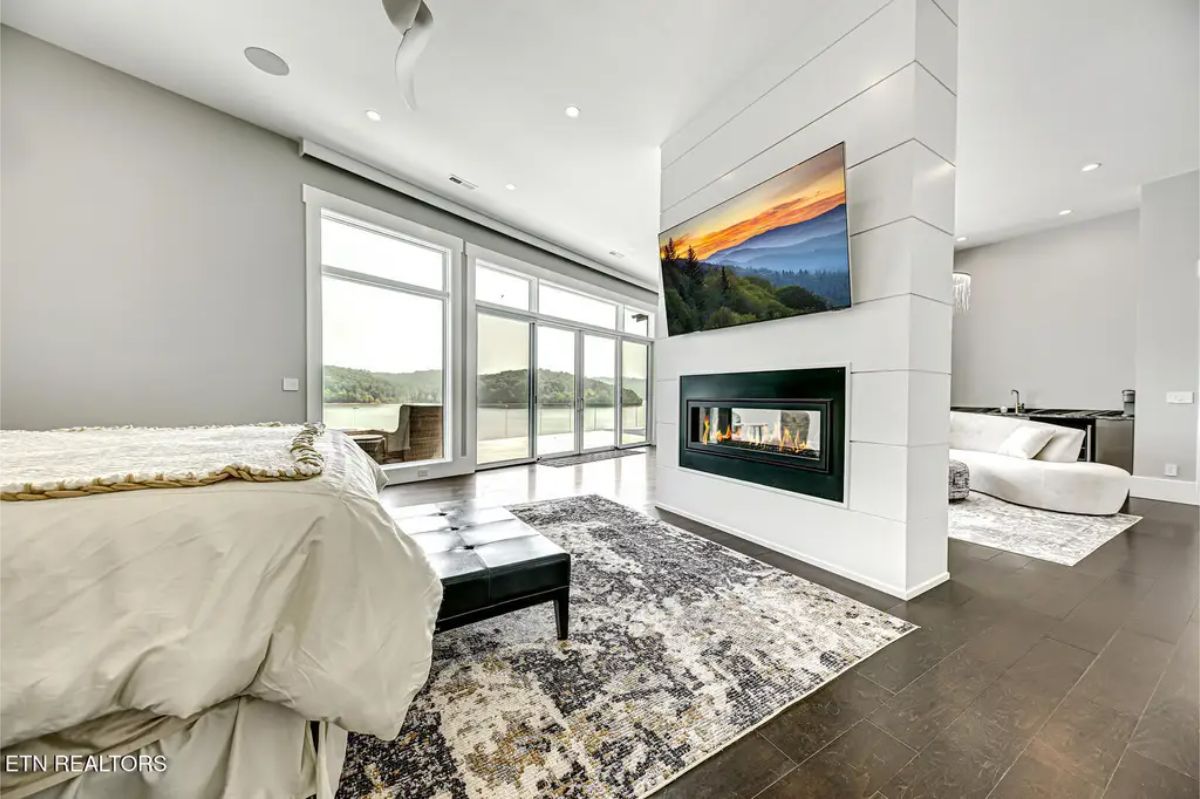 Expansive master suite featuring a double-sided fireplace, large windows, and a connected en-suite bathroom. 