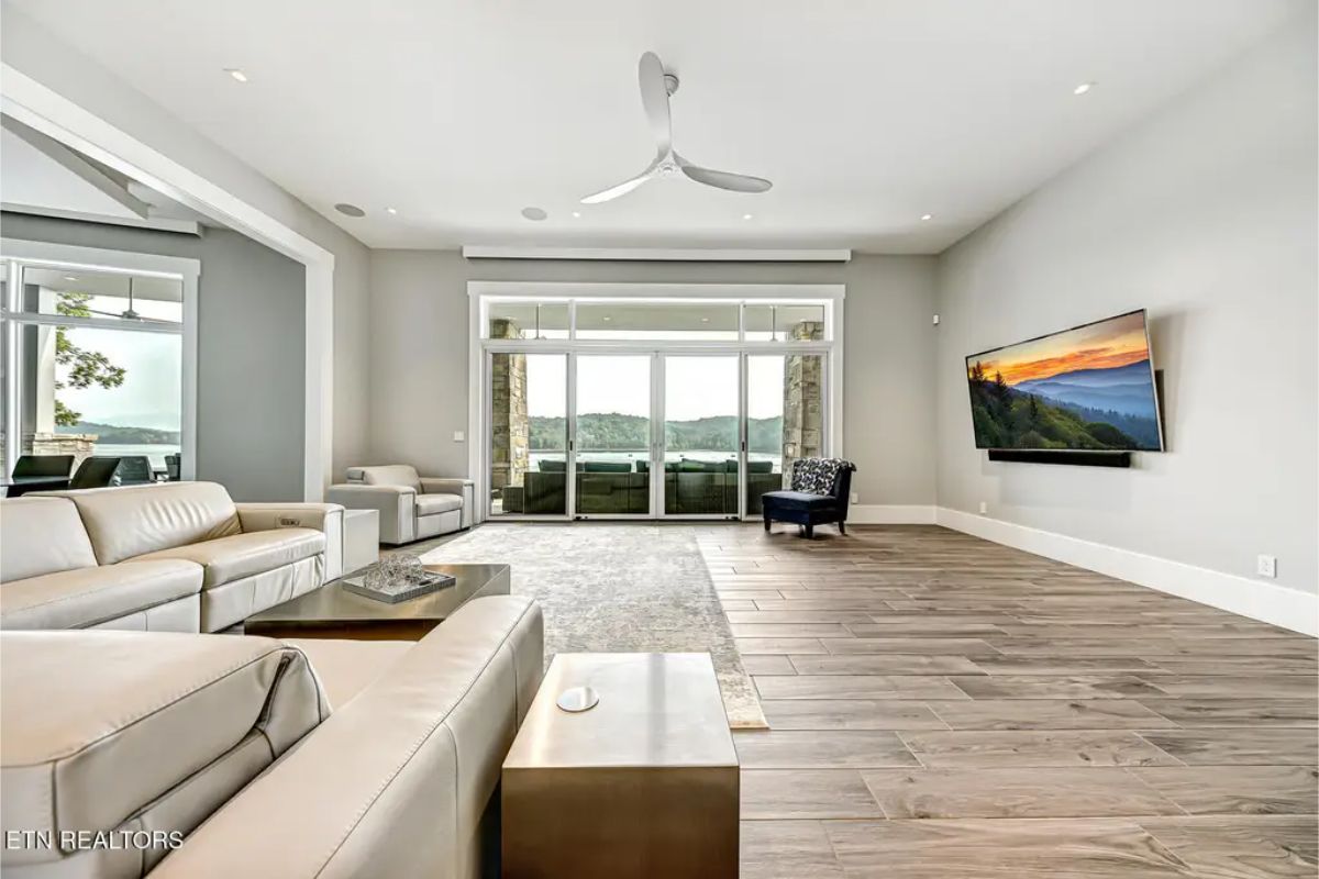 Spacious living room with a minimalist design, large windows, and an open view leading to the outdoor patio. 