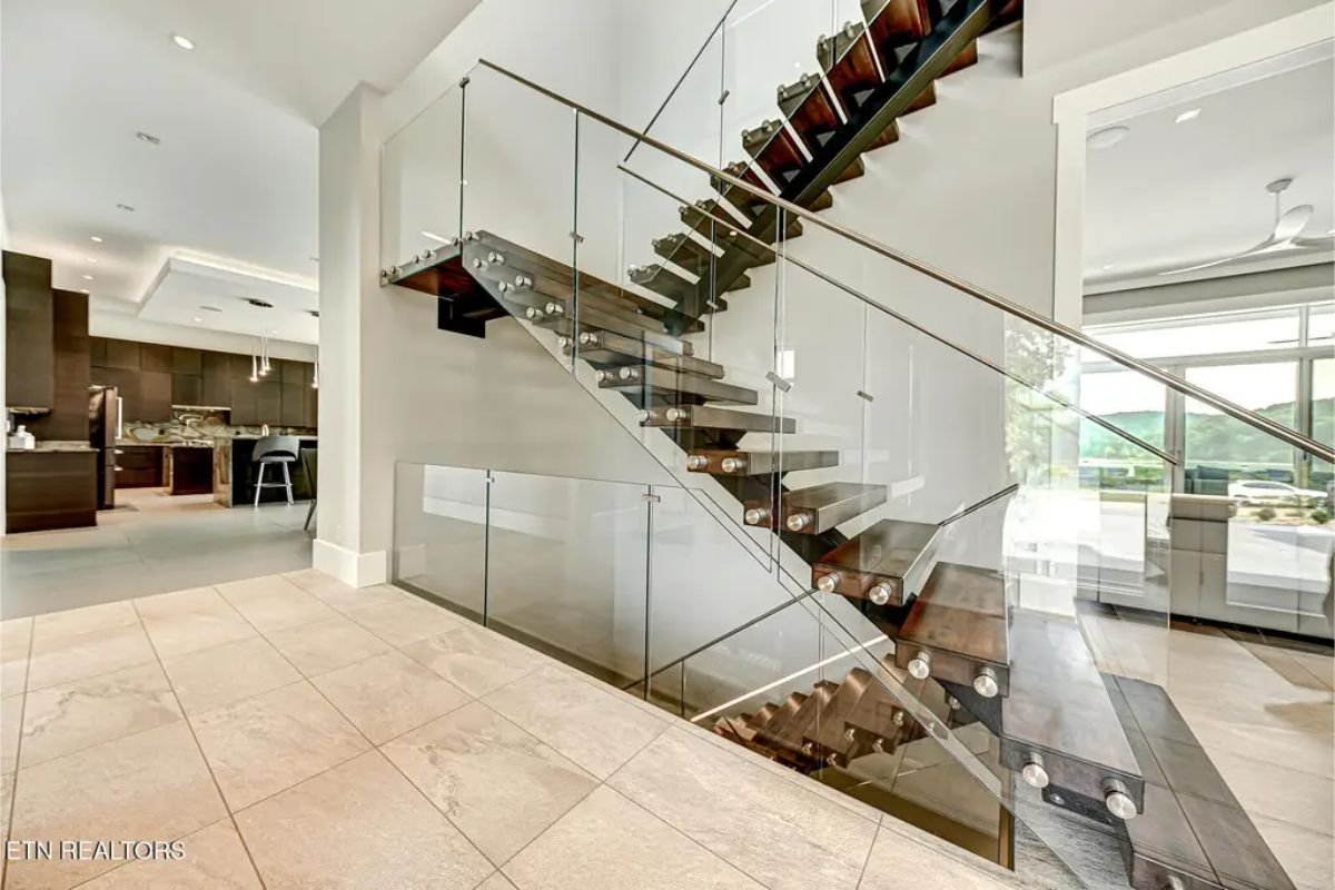 Contemporary staircase with floating wooden steps, glass paneling, and an open layout creating an airy feel. 
