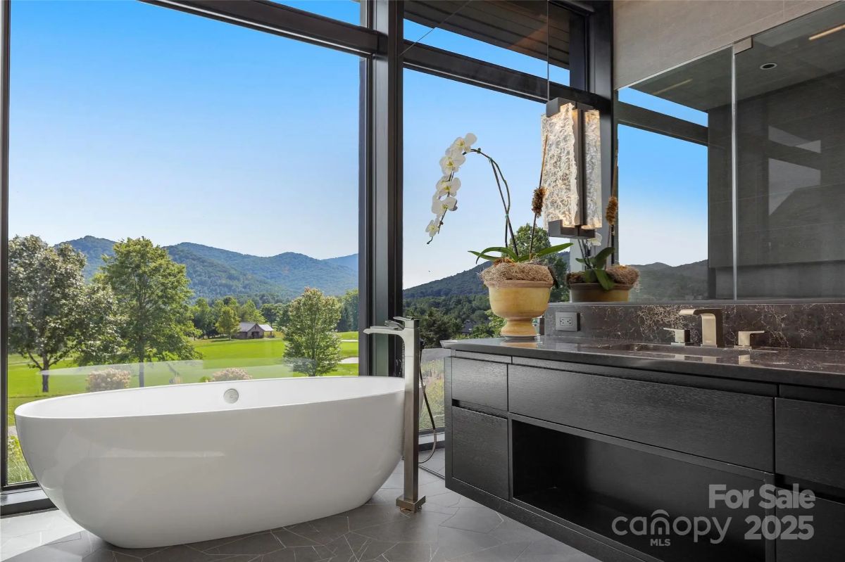 A freestanding tub sits perfectly against a glass wall, turning bathtime into a private mountain escape. 