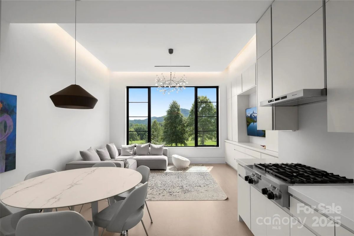 Crisp white interiors and oversized windows flood a modern living space with natural beauty. 