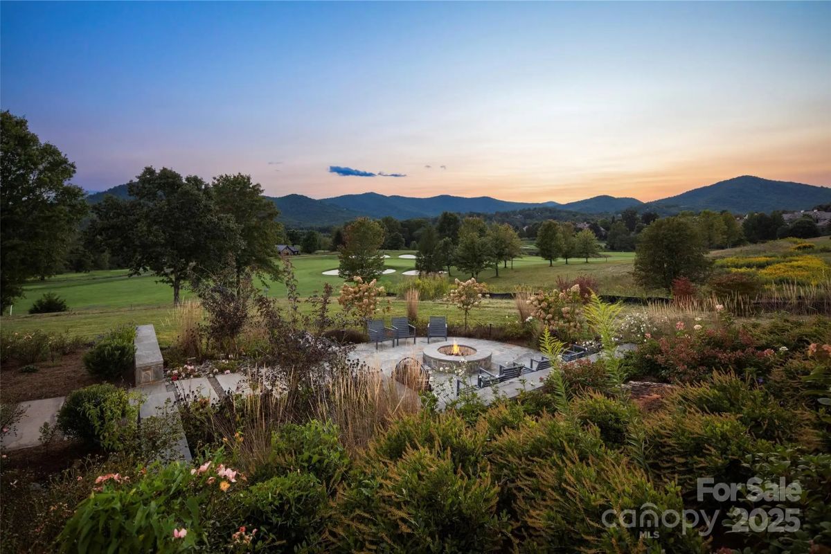 Sunset casts a warm glow over a private firepit, tucked into a garden of wild greenery. 