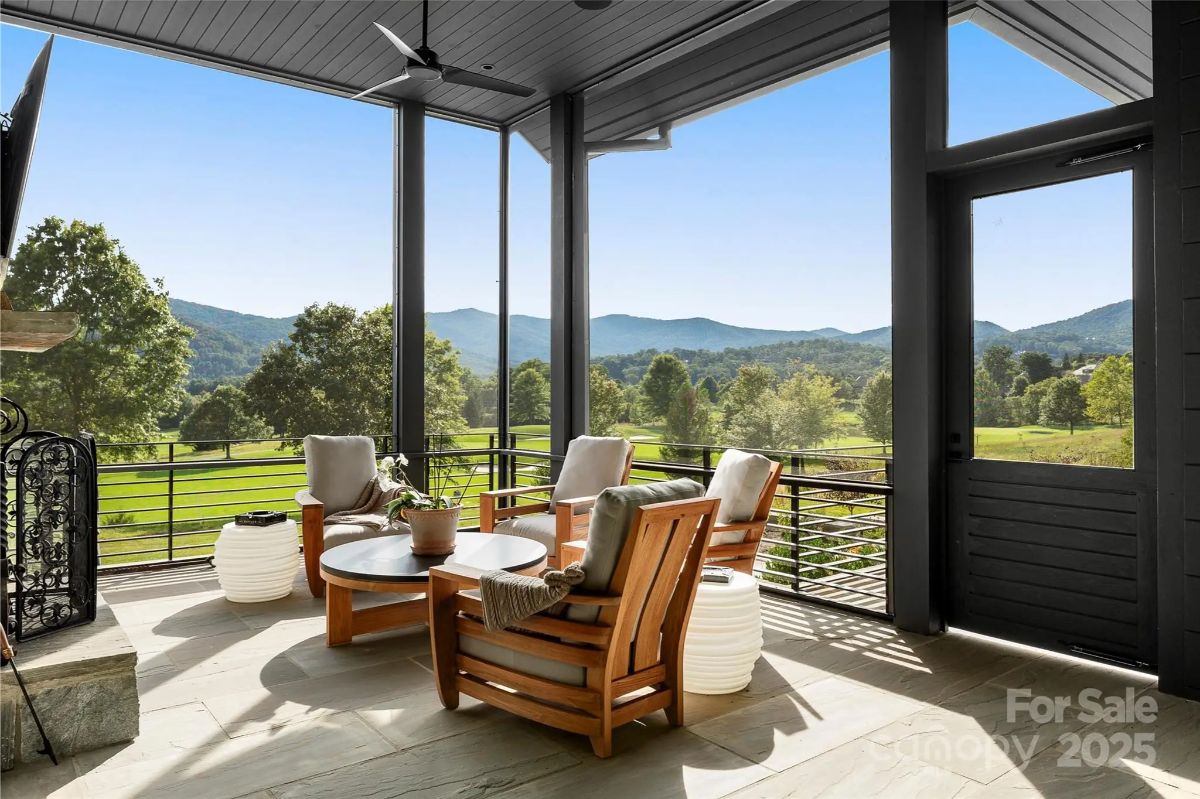 Cozy chairs circle a stone fireplace on a screened porch, where mountain views stretch endlessly. 