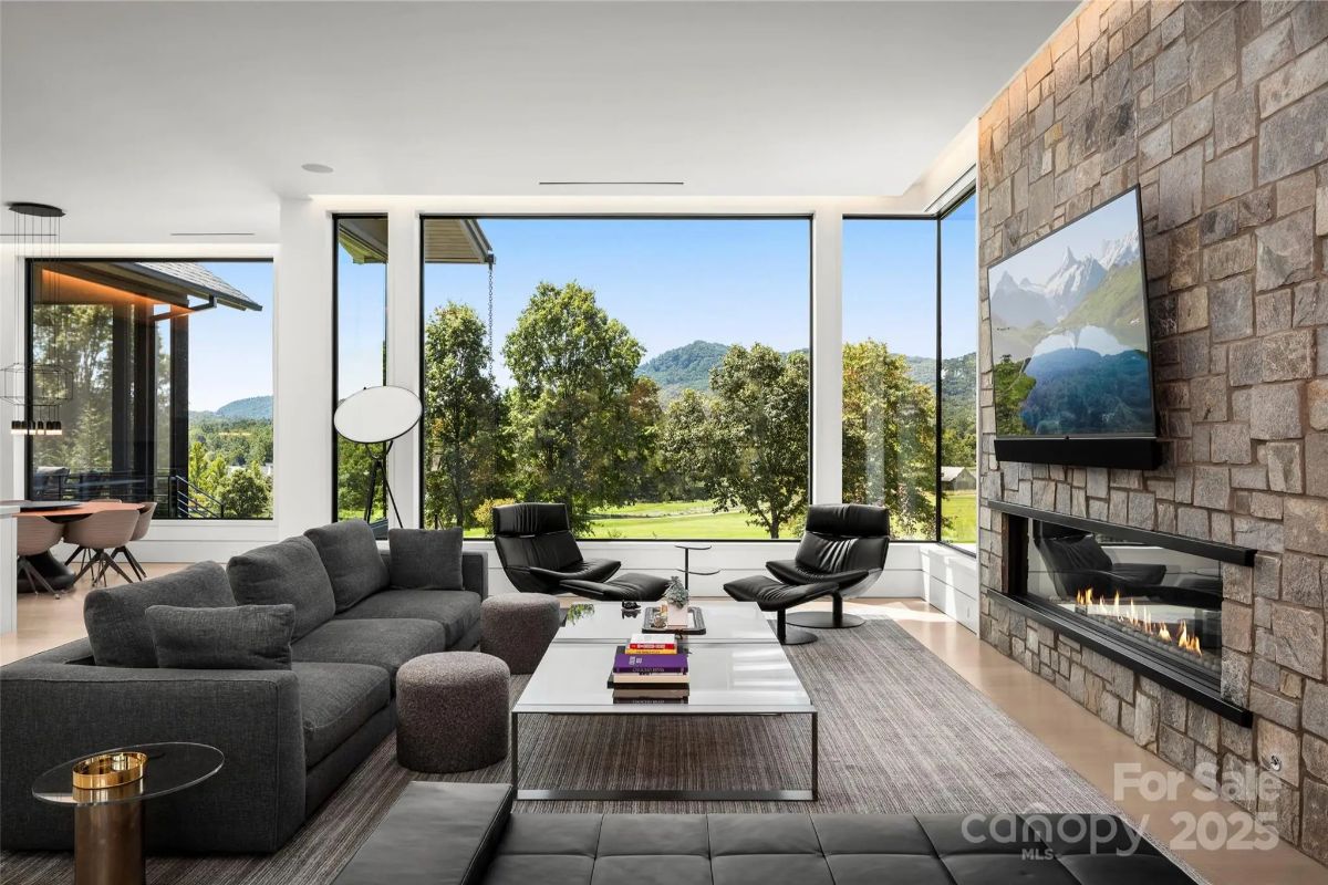 Dark stone and plush furnishings create a cozy yet sophisticated lounge overlooking endless greenery. 