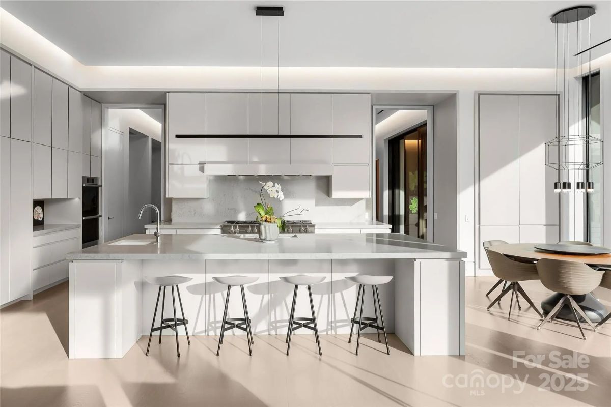 Minimalist white cabinetry and sleek finishes turn this kitchen into a vision of modern simplicity. 