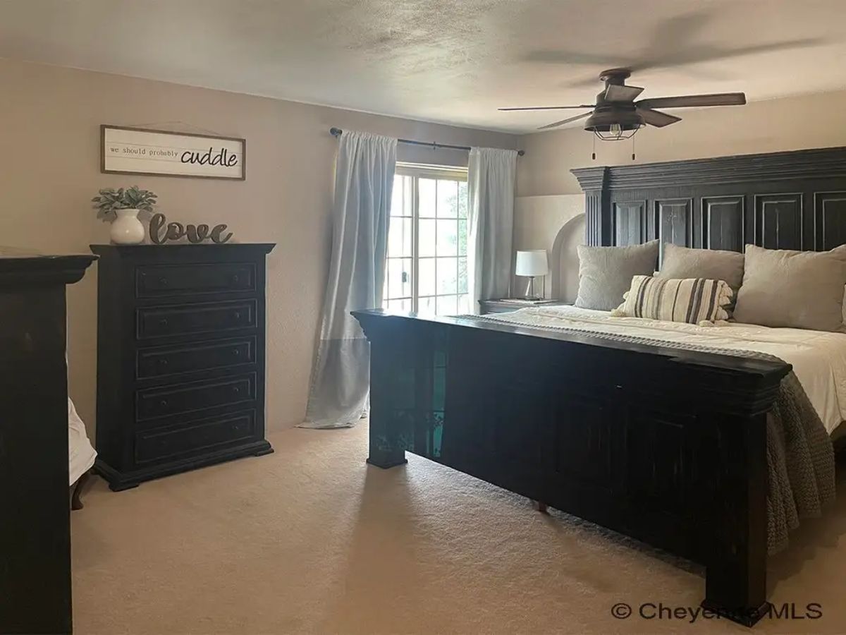 Dark wood bed frame and matching dresser contrast with neutral walls.
