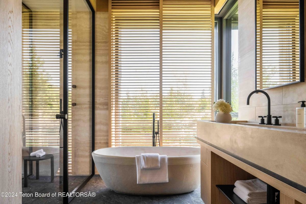 Spa-like bathroom featuring a freestanding tub, wood accents, and large windows with privacy blinds. 