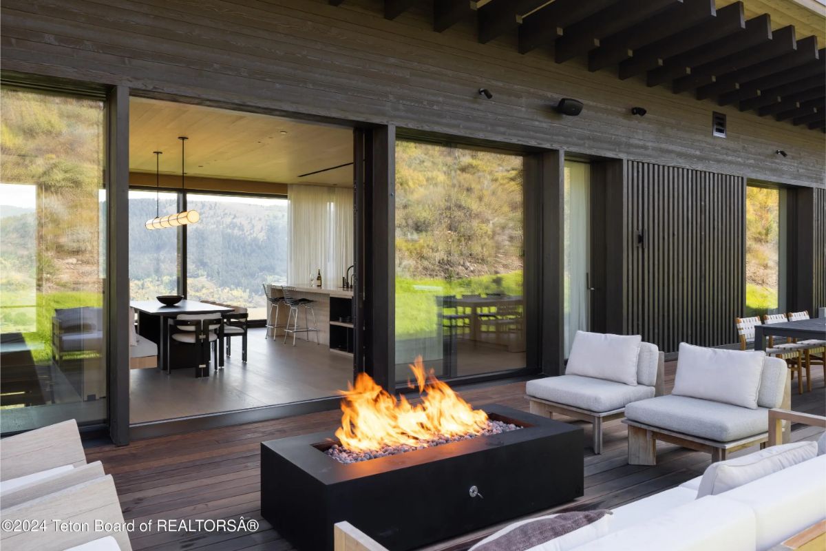 Outdoor living space with plush seating around a fire feature, seamlessly connecting to the indoor kitchen and dining area. 
