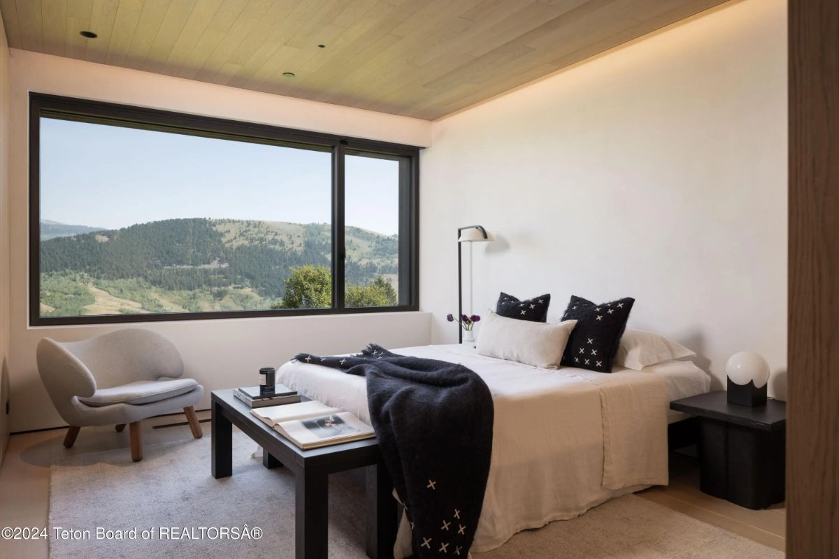 Minimalist bedroom with panoramic mountain views, sleek furnishings, and soft natural tones. 