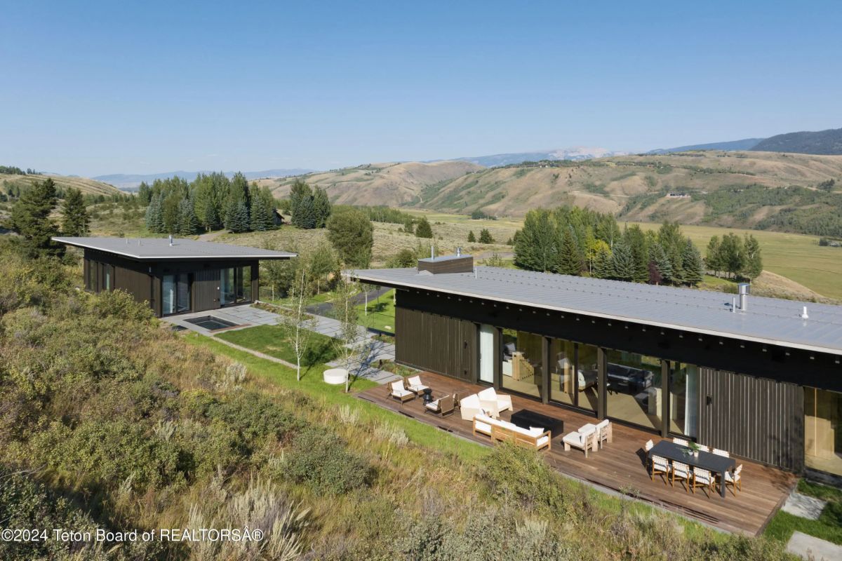 Aerial view of a contemporary compound with multiple structures, large decks, and sweeping vistas of rolling hills. 