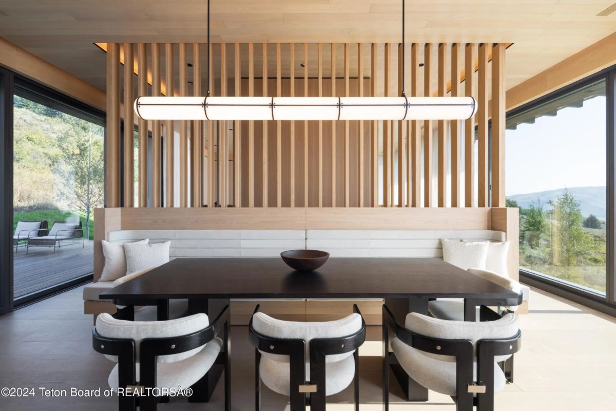Modern dining area with a black table, built-in bench seating, and floor-to-ceiling windows on either side. 
