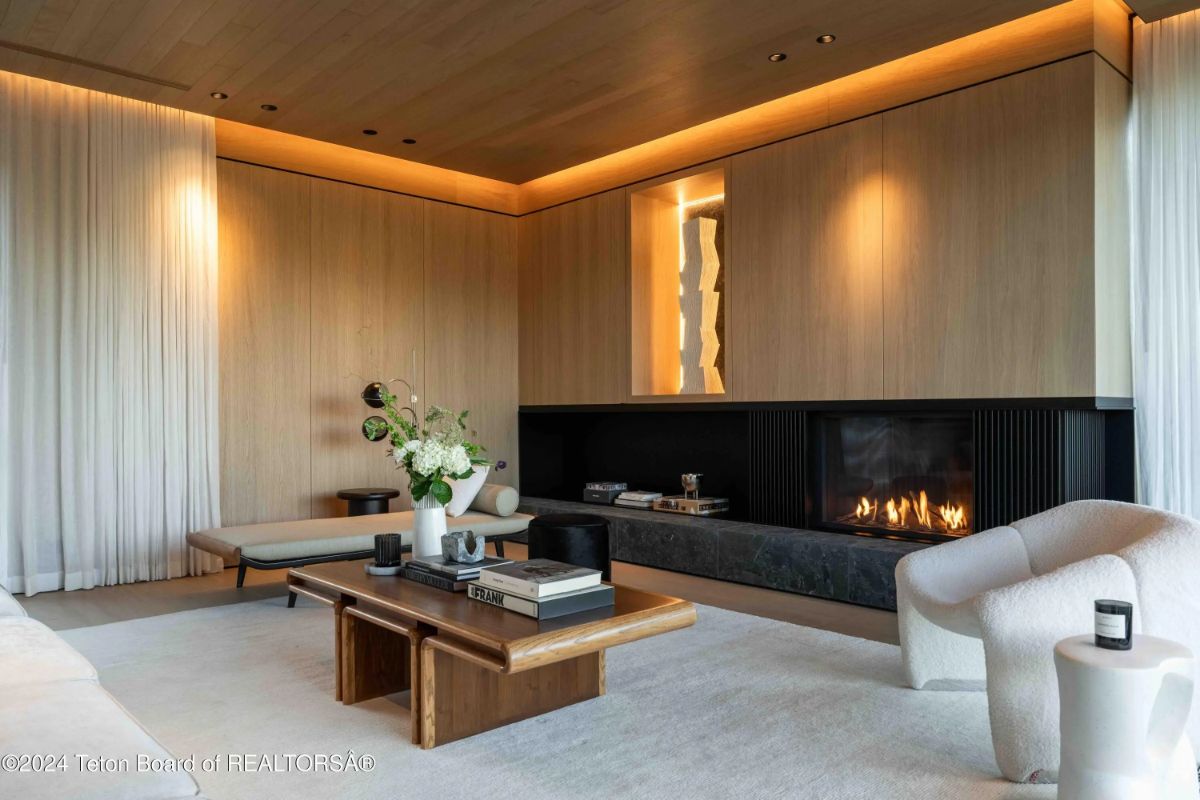 Cozy yet elegant living space with wood-paneled walls, recessed lighting, and a minimalist fireplace. 