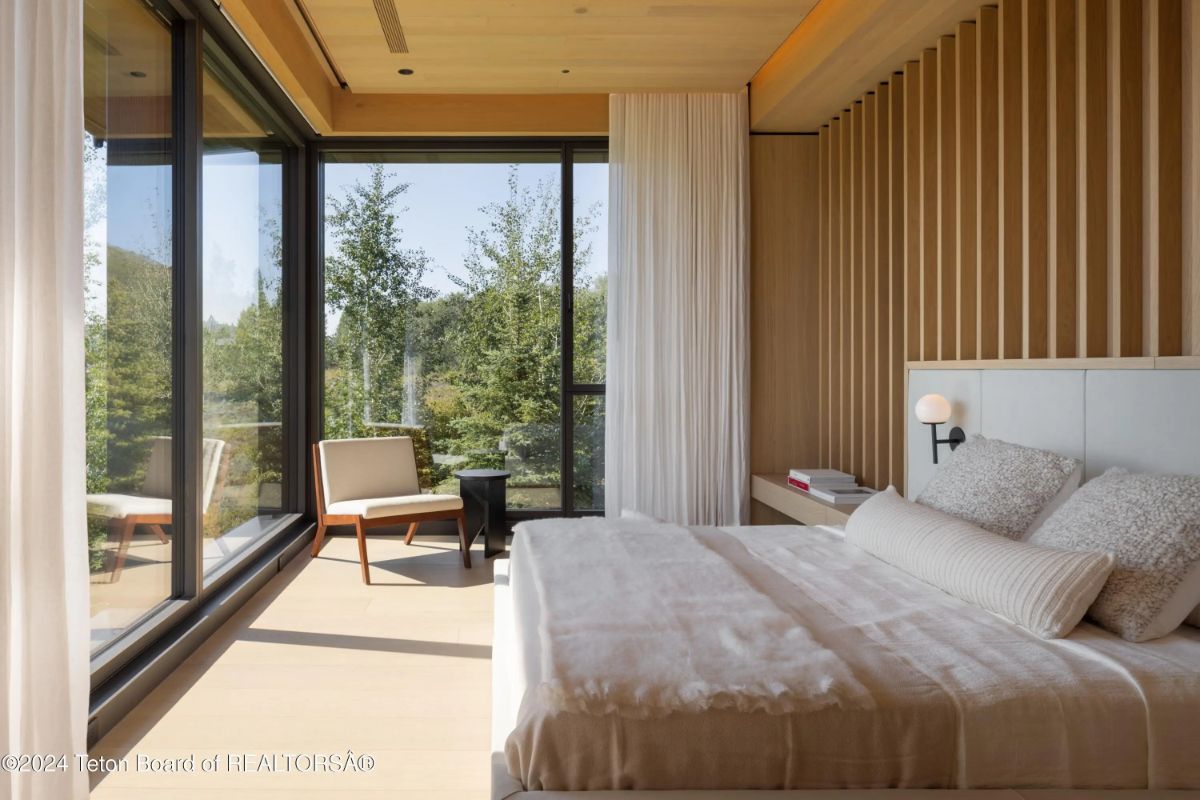 Minimalist bedroom with soft tones, full-height windows, and access to a private terrace. 