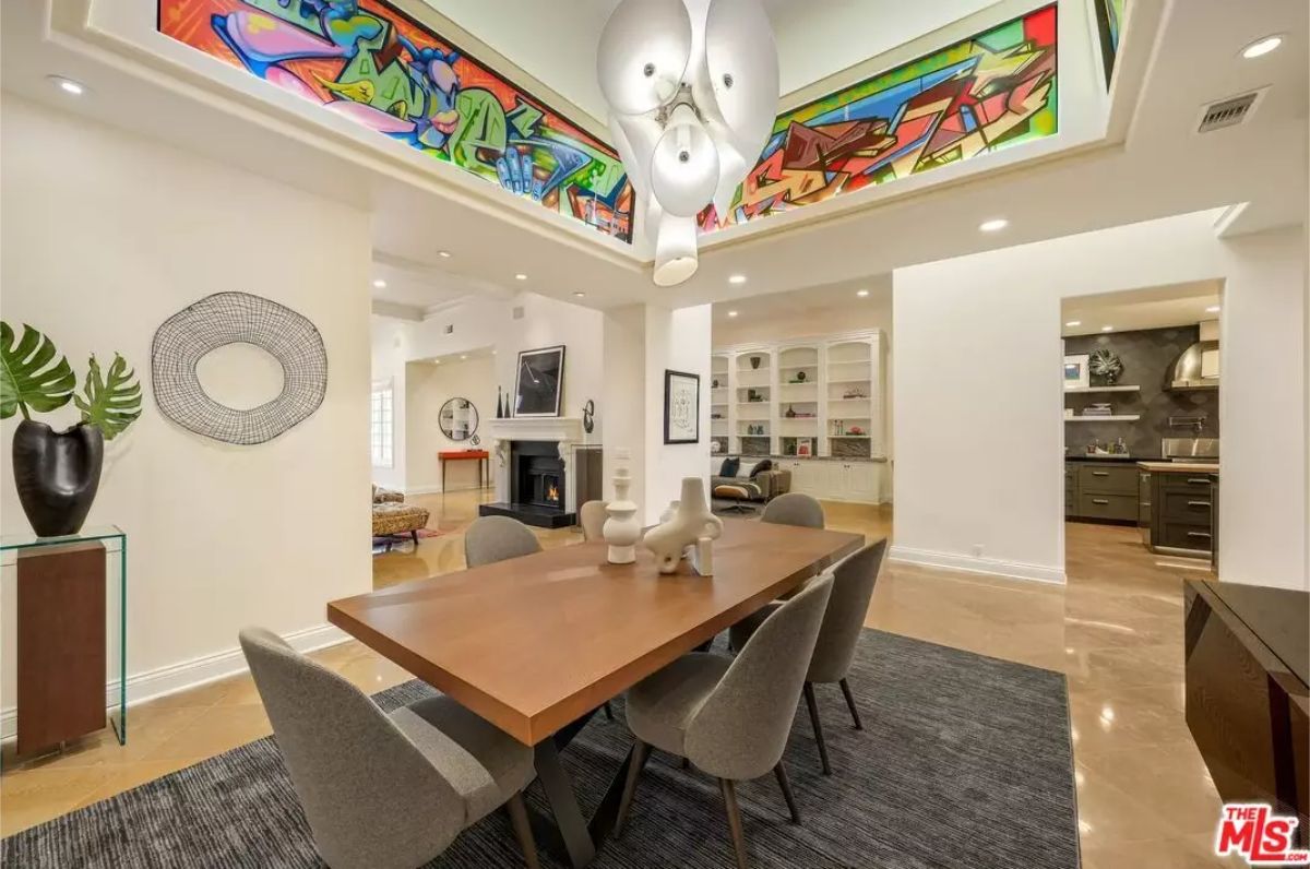 Dining space holds a wood table with six upholstered chairs on a dark rug.