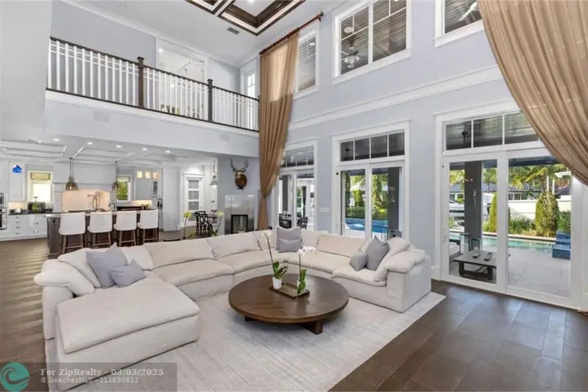 Double-height ceiling and full-length windows open to the backyard and pool.