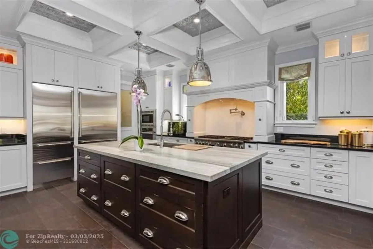White cabinetry contrasts with a dark wood center island topped with light marble.