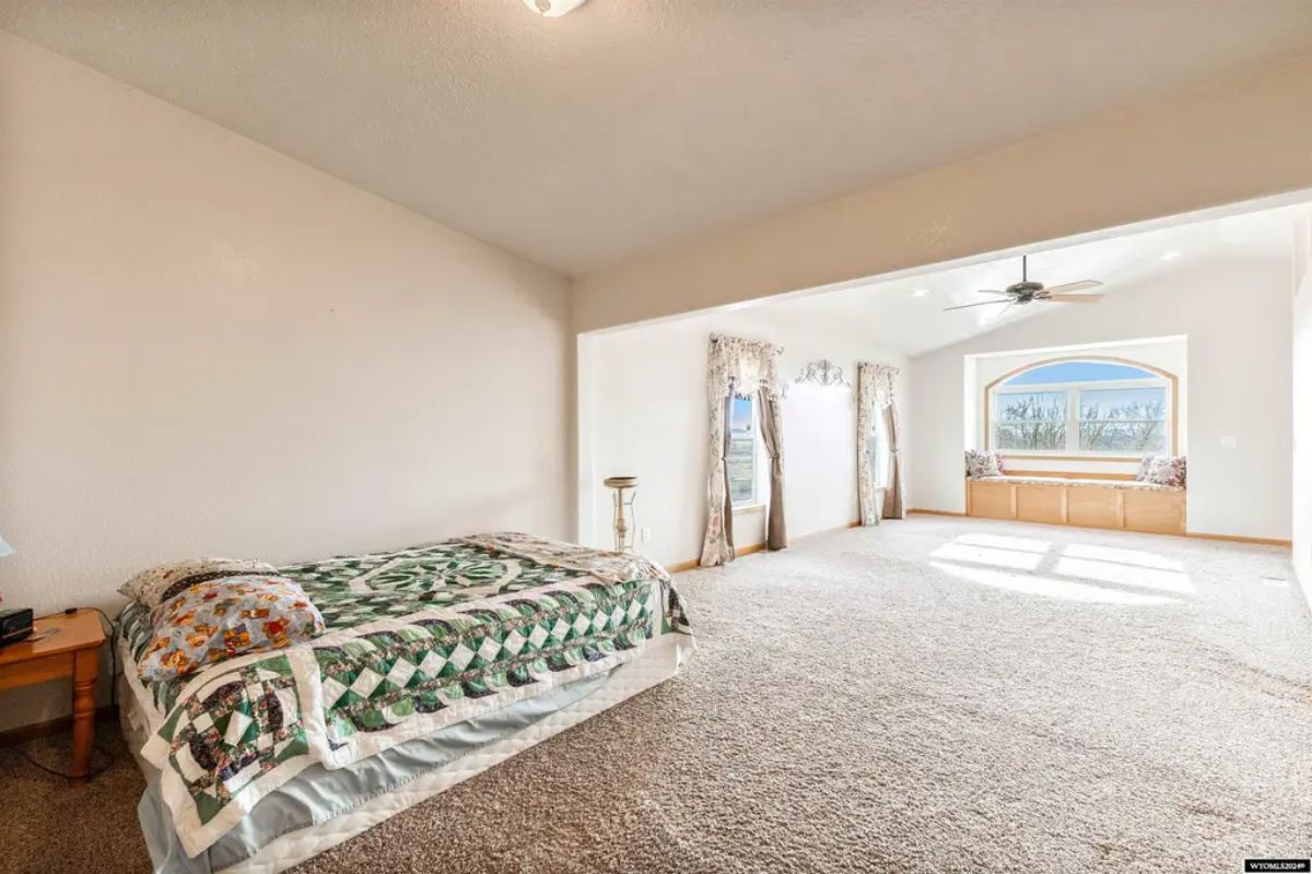 Spacious sleeping area has a bed placed against a plain white wall.