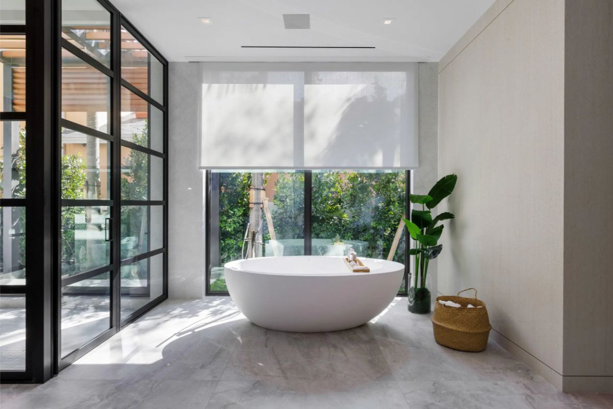 Serene bathroom with a soaking tub nestled beside floor-to-ceiling windows. 