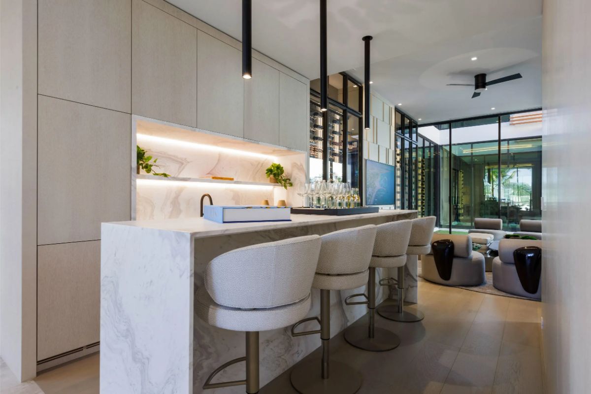 Cozy bar area with elegant lighting and marble accents adjacent to a living space. 