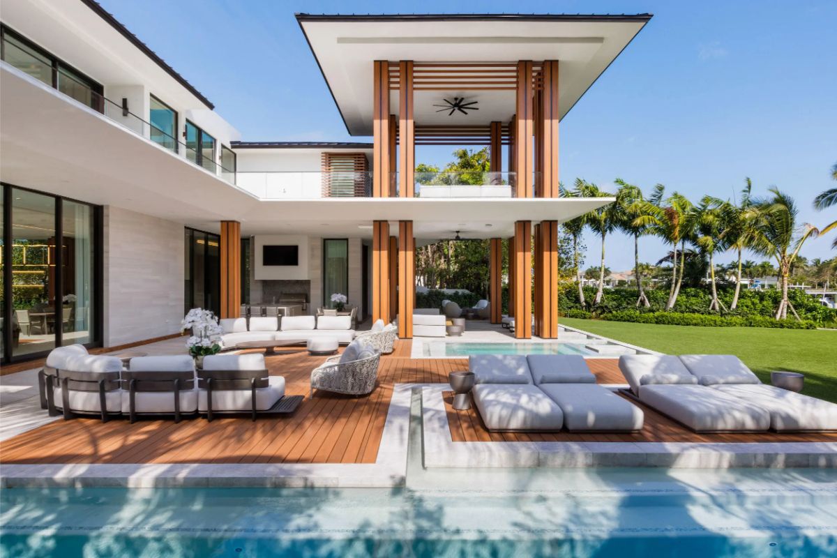 Designer pool deck with sunken loungers, palm-lined lawn, and striking columns. 