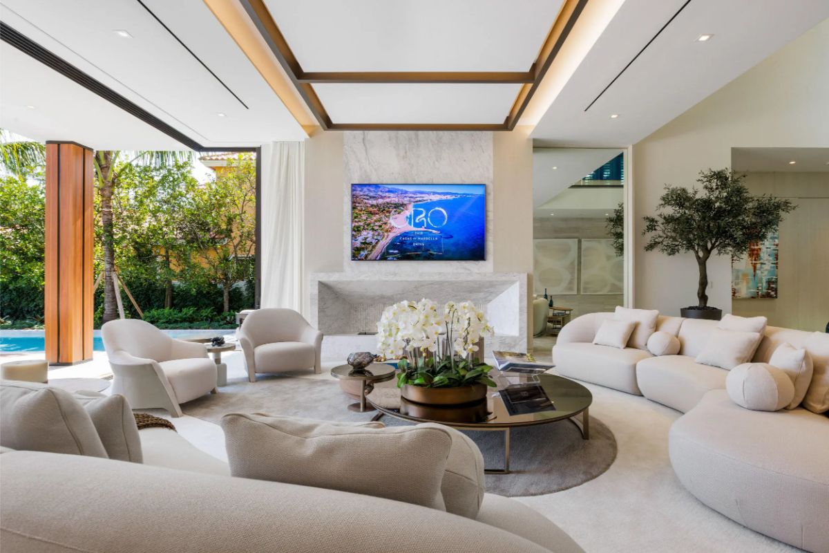 Cozy and elegant living room centers around a marble fireplace with soft, rounded furniture. 