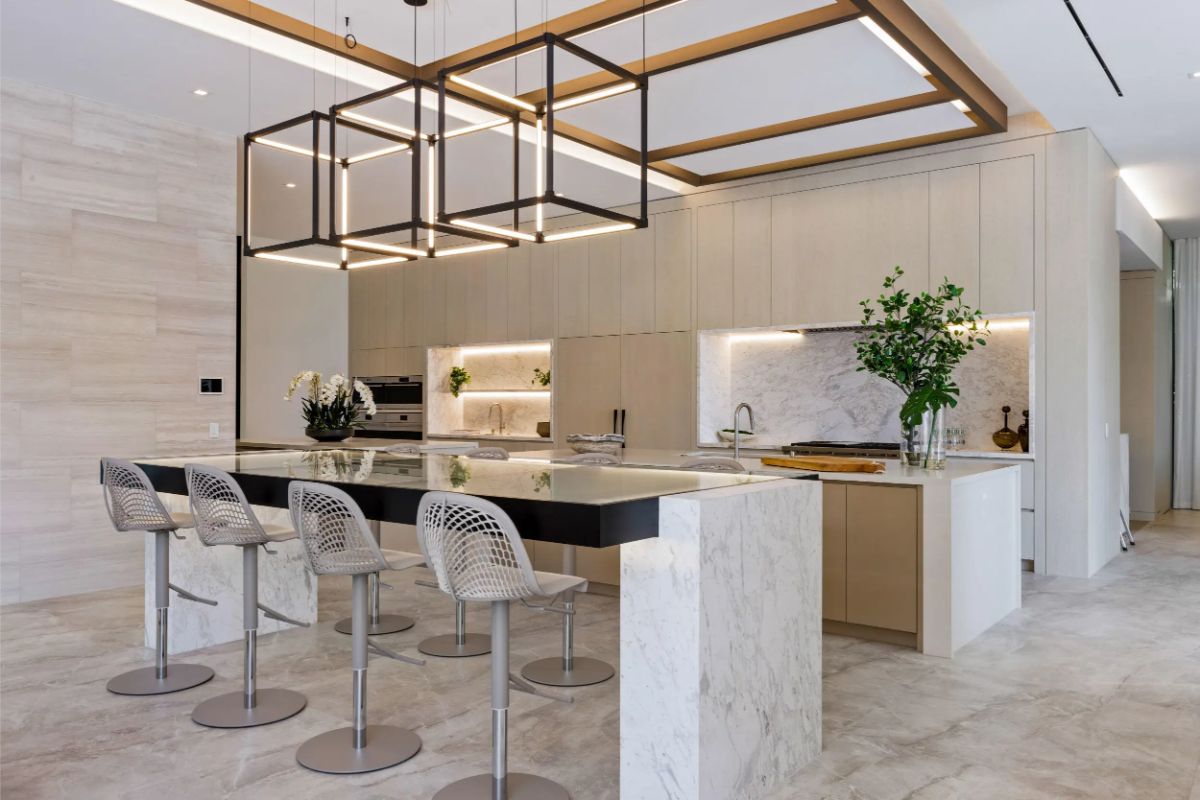 Ultra-modern kitchen boasts a marble island, unique pendant lighting, and a sleek neutral palette. 
