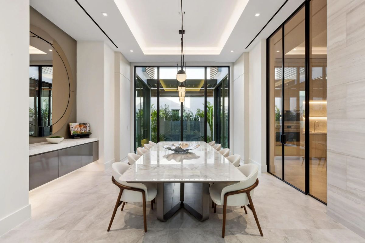 Formal dining room is sleek and sophisticated with tall windows and a glowing chandelier. 