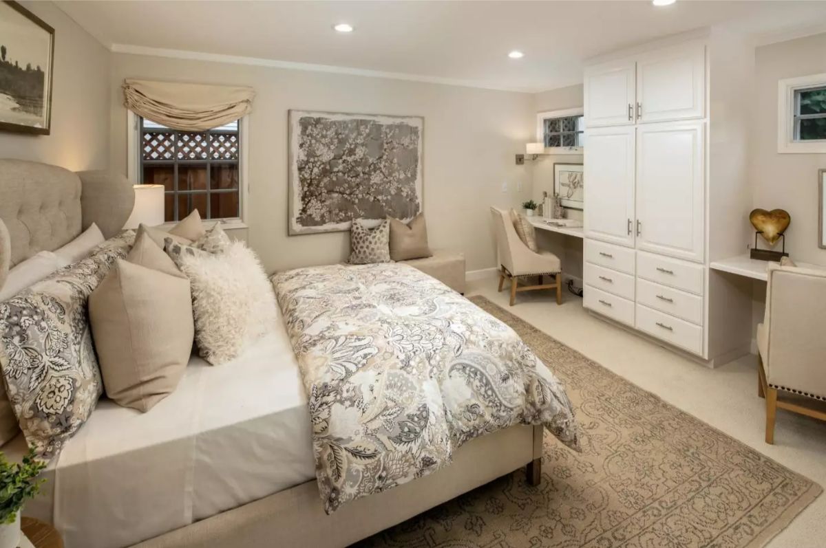 Patterned comforter covers a tufted bed with layers of neutral pillows.