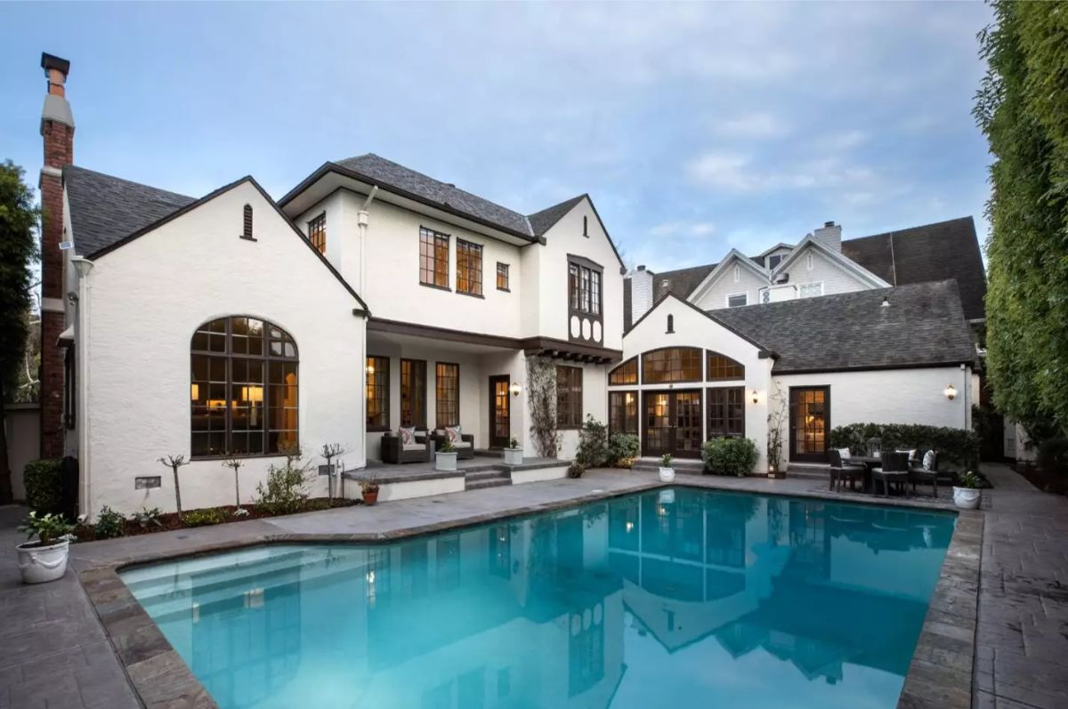 Rectangular pool is surrounded by concrete decking and privacy hedges.