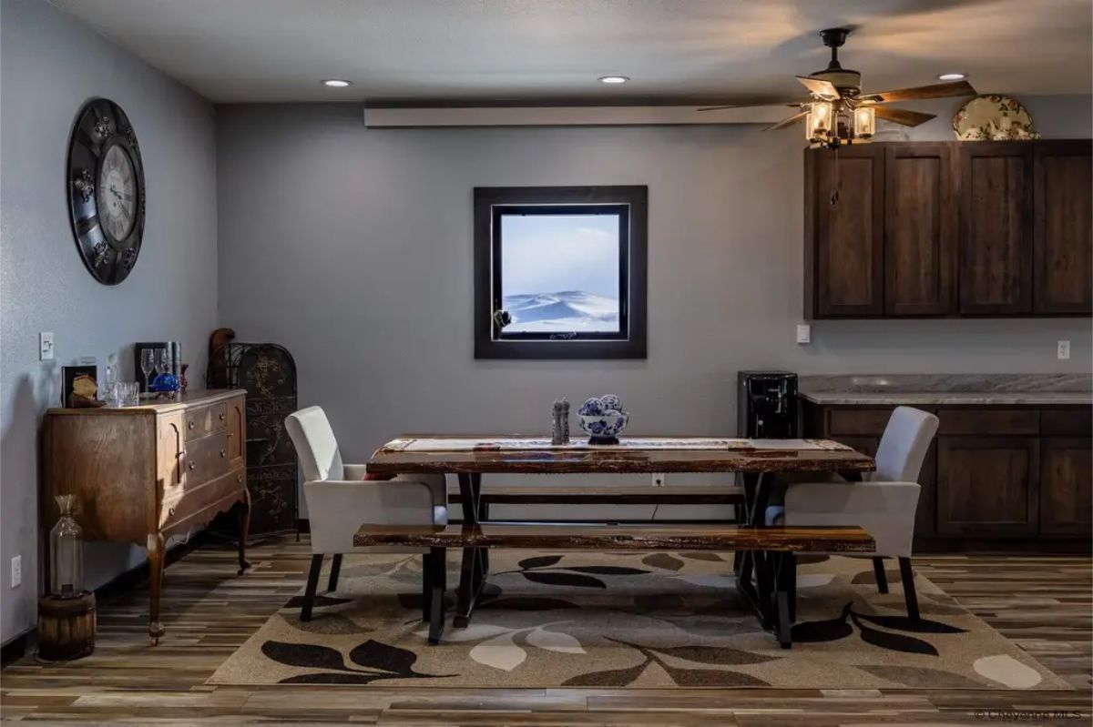 Wooden picnic-style table with matching benches is placed on a patterned rug.