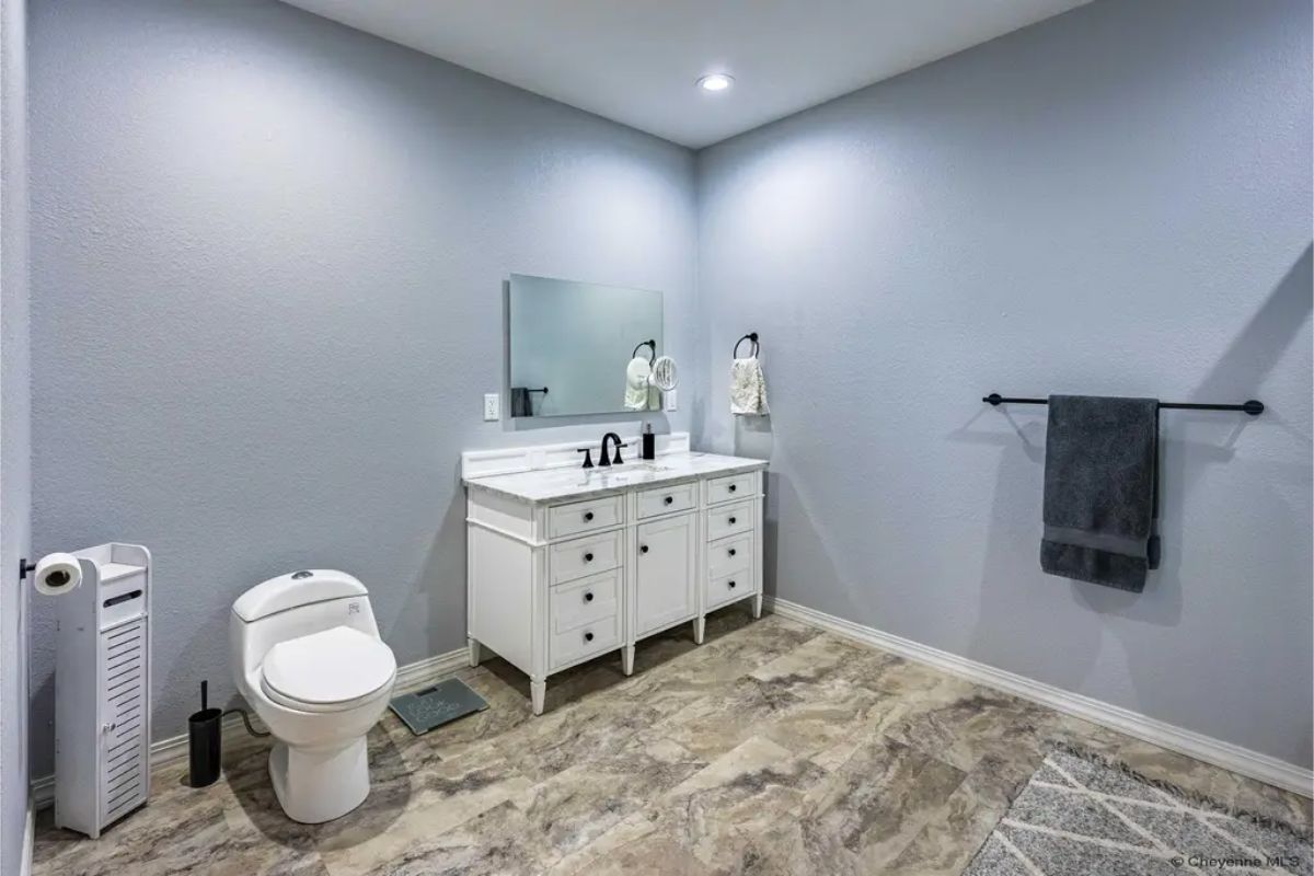 White vanity with a single sink is positioned against a gray wall.