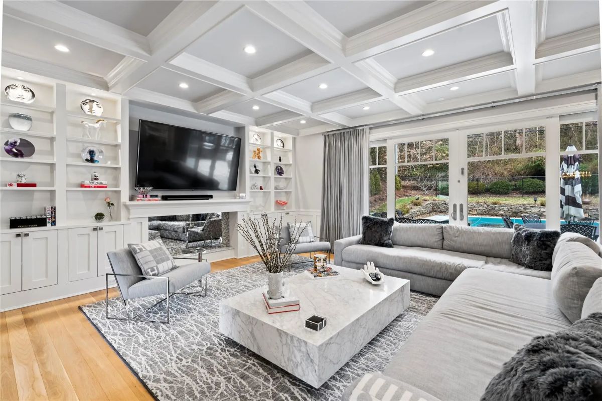 Coffered ceiling and recessed lighting highlight a large sectional facing the fireplace and TV.