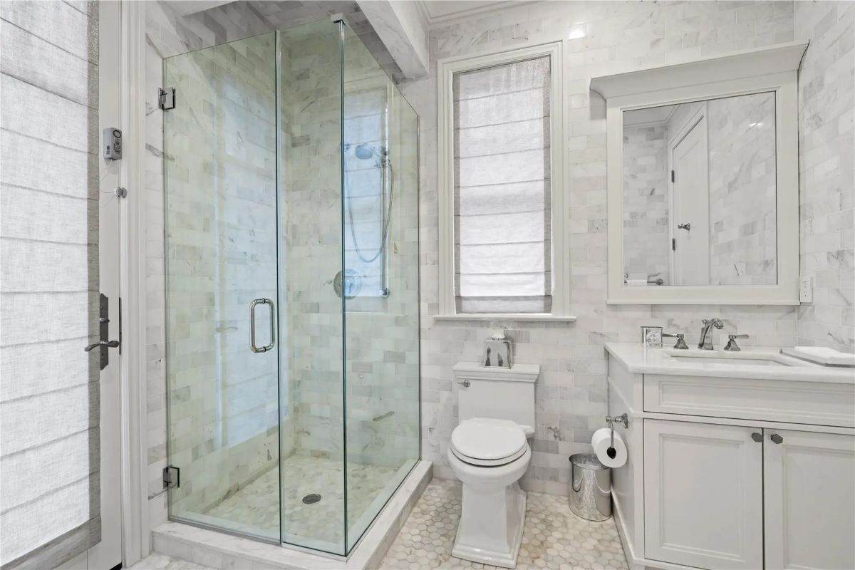 Walk-in glass shower sits across from a toilet and single vanity.