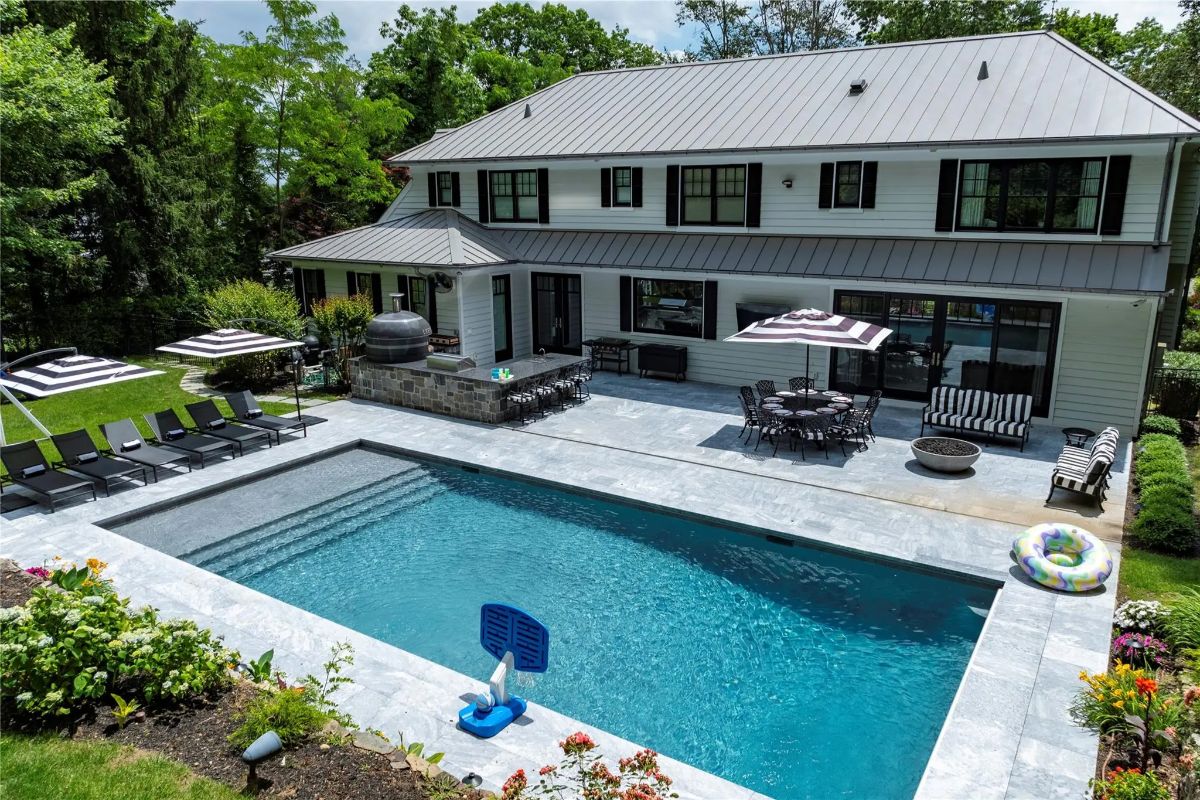 Rectangular pool is bordered by stone decking and landscaped garden beds.