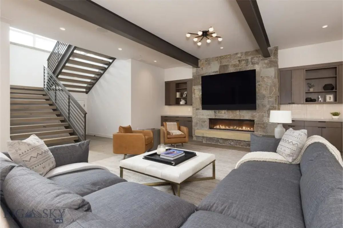 Comfortable media room showcases a built-in fireplace, large sectional sofa, and a mounted flat-screen TV for entertainment.