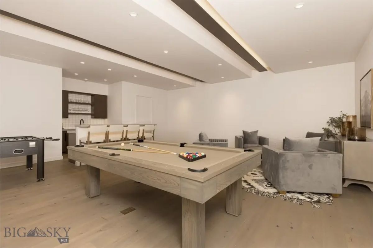 Game room includes a pool table, foosball, and a bar area, creating a spacious spot for relaxation and fun.