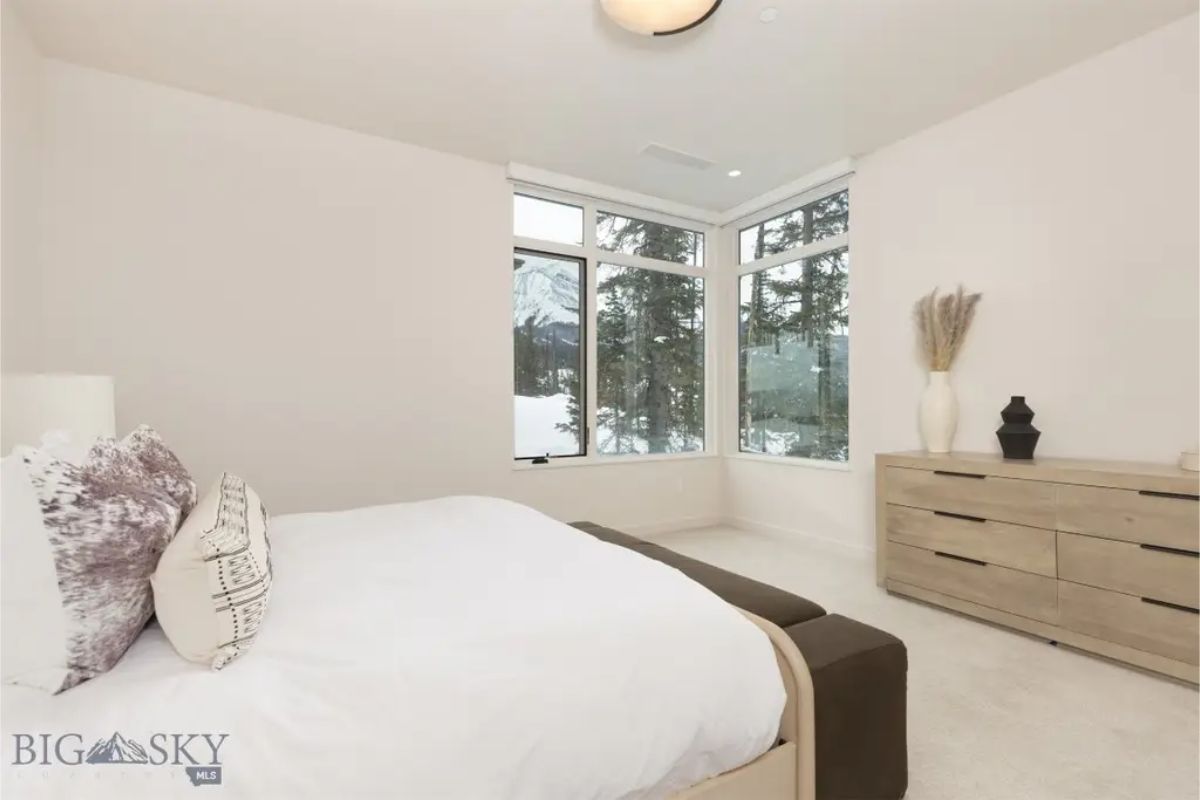 Inviting bedroom with corner windows offering stunning views of the snowy landscape.